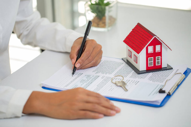 Une femme signe un contrat pour acheter une maison avec un bien immobilier a
 - Photo, image