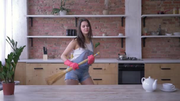 household chores, cheerful housewife girl fooling around and dancing in broomstick during House cleaning - Imágenes, Vídeo