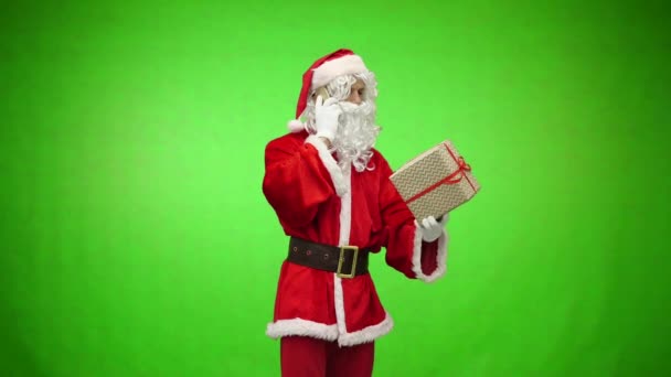 Santa Claus with gift speaks on the phone, green chromakey in the background - Кадри, відео