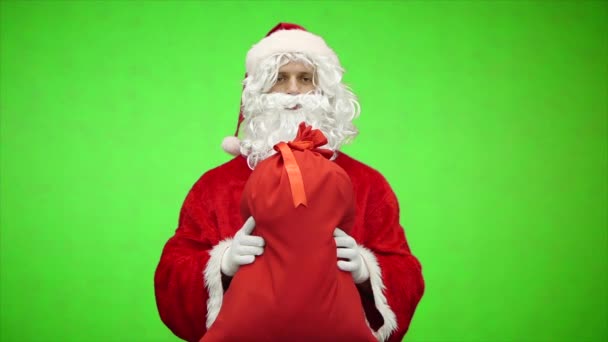 Portrait of Santa Claus give bag with gifts on green background. Slow motion. - Footage, Video
