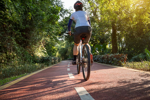 Woman cycling on bike path at park on sunny weather - Valokuva, kuva