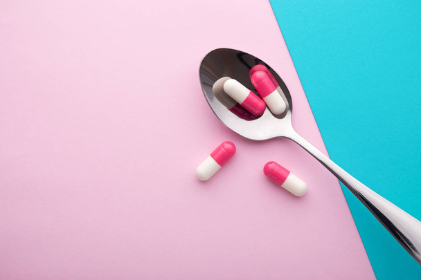 Харчова добавка, таблетки в ложці на рожевому фоні
 - Фото, зображення