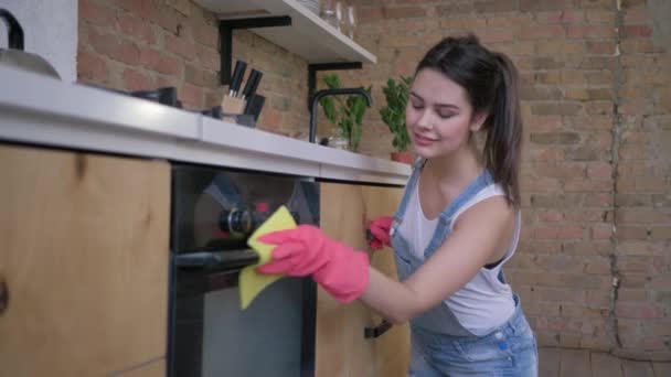 prace domowe, młoda gospodyni domowa w gumowych rękawiczkach do czyszczenia zakurzonych mebli - Materiał filmowy, wideo