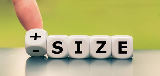 Hand turns a dice and changes the expression "- size" to "+ size - Photo, Image