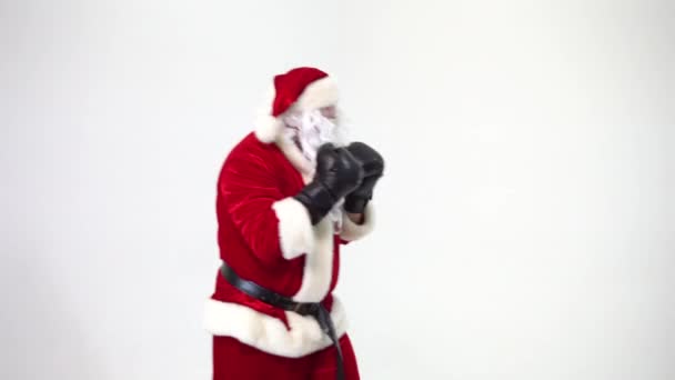 Christmas. Santa Claus on a white background wears black boxing gloves and fulfills punches. Kickboxing, fighter. - 映像、動画