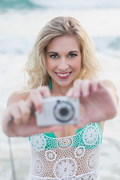 Amused blonde woman in beach dress taking a picture - Фото, изображение