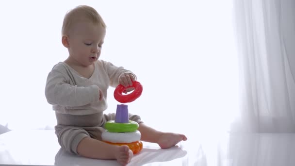 nieuwsgierig peuter jongen gespeeld met educatieve speelgoed toren in lichte kamer - Video