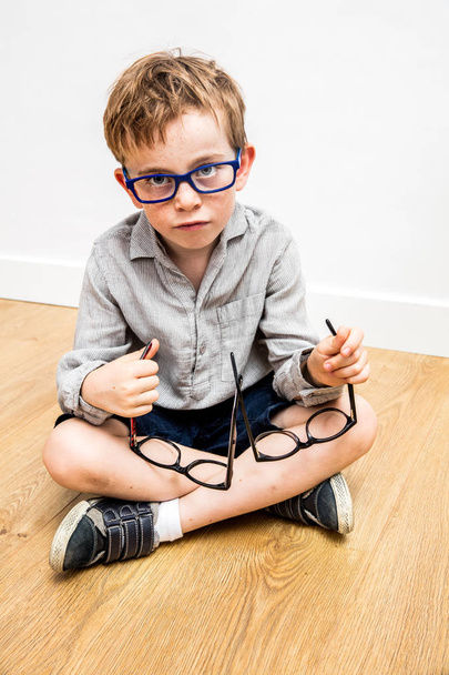 confused boy with many eyeglasses in hands picking eye care - 写真・画像
