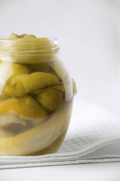 Pimentos verdes fermentados em um jarro em um fundo branco. espaço de cópia
 - Foto, Imagem