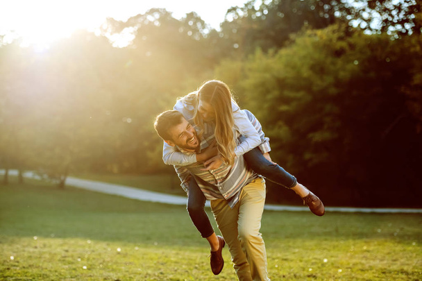 Cute caucasian couple in love having piggyback and having fun in nature. - Foto, Imagem