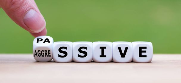 Hand turns a dice and changes the word "passive" to "aggressive" - Photo, Image