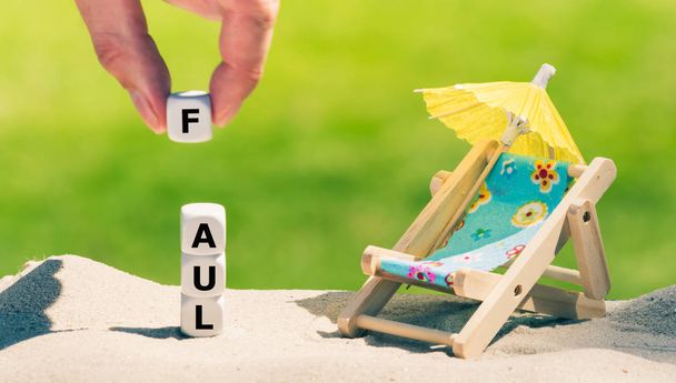 Los dados colocados junto a una silla de playa forman la palabra alemana "FAUL
" (" - Foto, Imagen