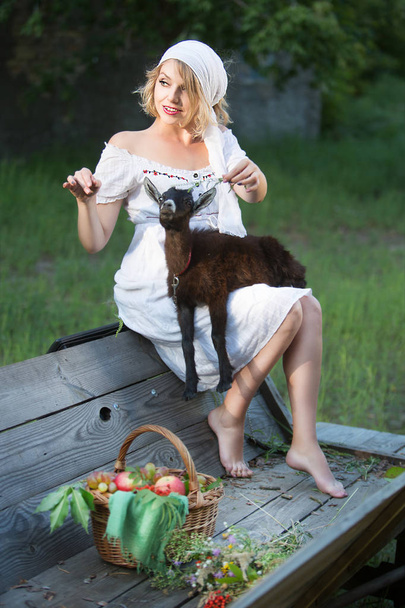 Une belle jeune femme nourrit une petite chèvre. Vie rurale
 - Photo, image