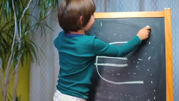 Boy draws on the blackboard near the euro sign - Кадры, видео