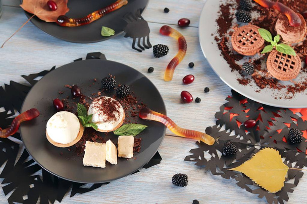Nourriture d'Halloween, feuilles d'automne et dessert au chocolat, crème glacée et vers à gelée sur une table en bois
 - Photo, image