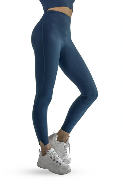 Mooie slanke vrouwelijke benen in blauwe sport leggings en hardloopschoenen geïsoleerd op witte achtergrond. Concept van stijlvolle kleding, sport, schoonheid, mode en slanke benen - Foto, afbeelding