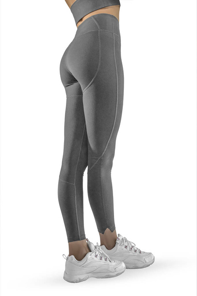schöne schlanke Frauenbeine in grauen Sport-Leggings und Laufschuhen isoliert auf weißem Hintergrund. Konzept aus stilvoller Kleidung, Sport, Schönheit, Mode und schlanken Beinen - Foto, Bild