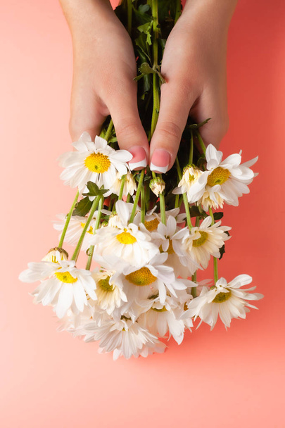 İnce genç eller, ince bilekli, temiz ciltli ve Fransız manikürlü çiçekleri tutuyor. Düz yatay fotoğraf, metin için yer. - Fotoğraf, Görsel