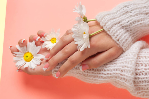 Slender young hands hold flowers, with a thin wrist, clean skin and French manicure. Flat lay photo, with place for text. - Foto, Imagen