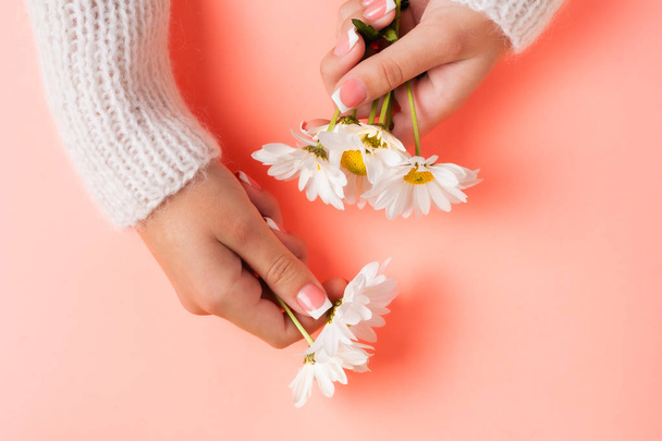 Slender young hands hold flowers, with a thin wrist, clean skin and French manicure. Flat lay photo, with place for text. - Fotoğraf, Görsel