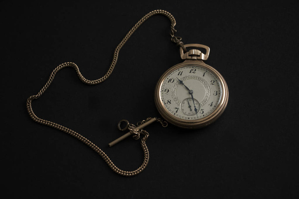 Ročníkové zlaté kapesní hodinky se zlatým řetízkem na černém pozadí - Fotografie, Obrázek