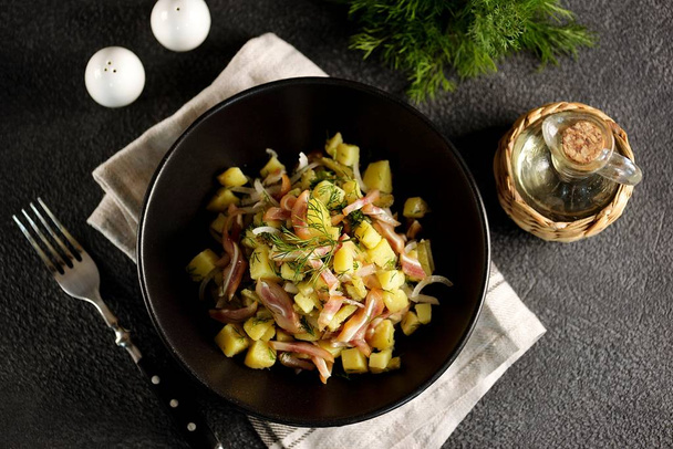 Salat aus geräucherten Schweineohren mit gekochten Kartoffeln, Gurken, Zwiebeln, Dill und Olivenöl. - Foto, Bild