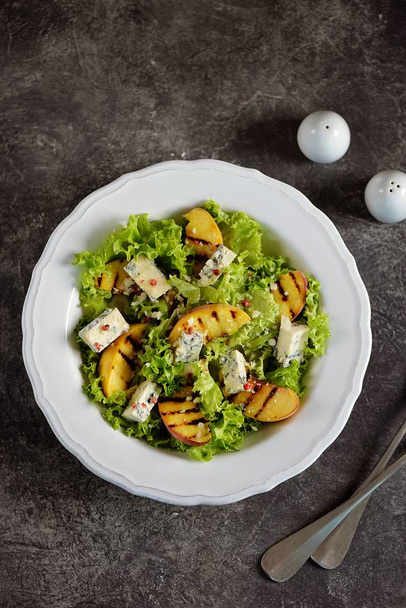 Marul, mavi peynir, parmesan, zeytinyağı ve pembe biberli ızgara şeftali salatası.. - Fotoğraf, Görsel