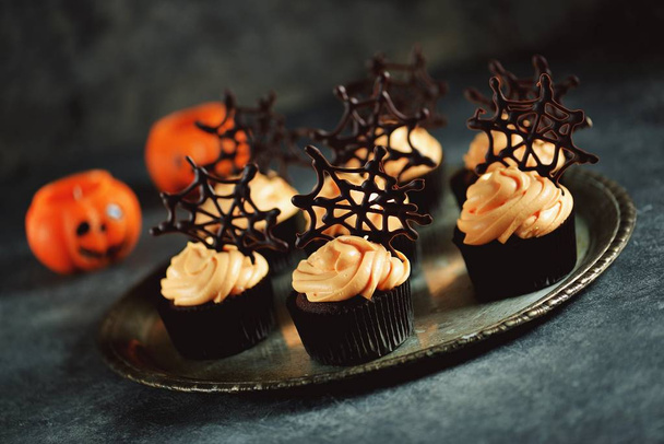Chocolate cupcakes with pumpkin cream and chocolate spider web. Dessert for Halloween. - Photo, Image