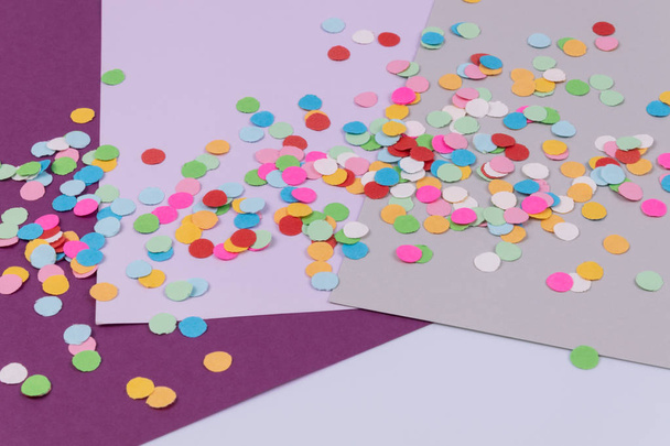 Kerek konfetti szürke, ibolya és lila paprika lapokra szórva - Fotó, kép