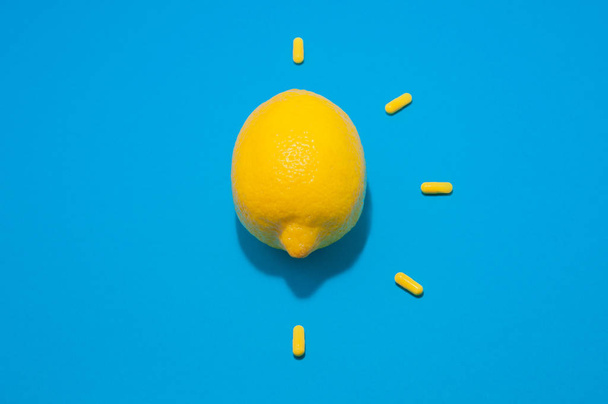 one yellow lemon and five pills on blue background - Foto, Bild