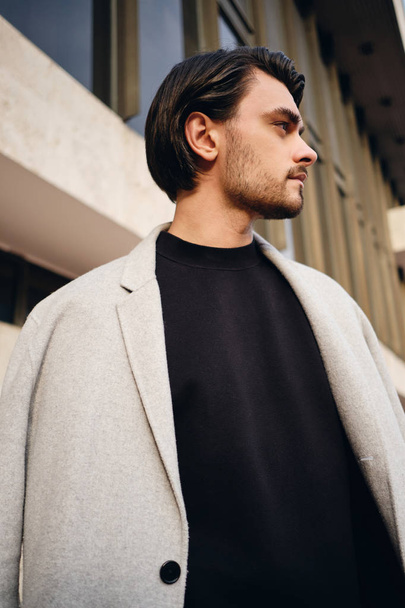 Side view of serious stylish brunette man in coat thoughtfully looking away outdoor - Foto, immagini