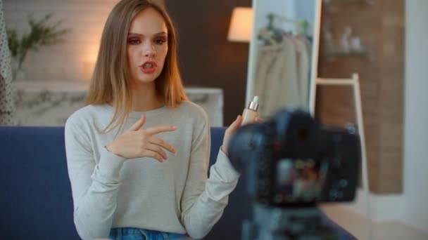 Een mooie jonge meisje make-up blogger praat over de techniek van het gebruik van highlighter borstels en schaduwen om make-up te maken. een camera op een statief neemt het interview op. - Video