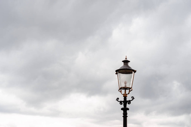 Utcai lámpás, top. A nehéz őszi szürke ég és a szürke esőfelhők hátterében. Vízszintes tájolás. - Fotó, kép