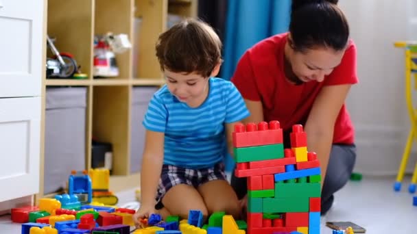 moeder spelen kleurrijke plastic blokken speelgoed met haar zoon, concept voor moeder en zoon samen spelen. - Video