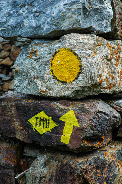 Lettres TMB signifiant Tour du Mont Blanc et une flèche de direction peinte sur un rocher. Une randonnée classique de plusieurs jours dans les Alpes françaises
 - Photo, image