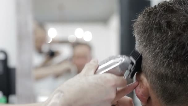 Miesten kampaus parturissa. Lähikuva mestari leikkaamalla mies mustat hiukset leikkuri
. - Materiaali, video