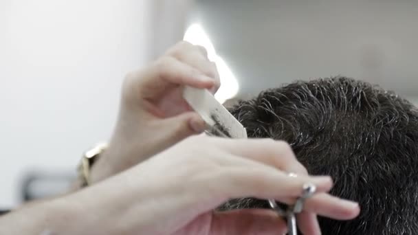 Pánský účes v holičství. Detailní záběr mistra stříhání muže s černými vlasy s nůžkami. - Záběry, video