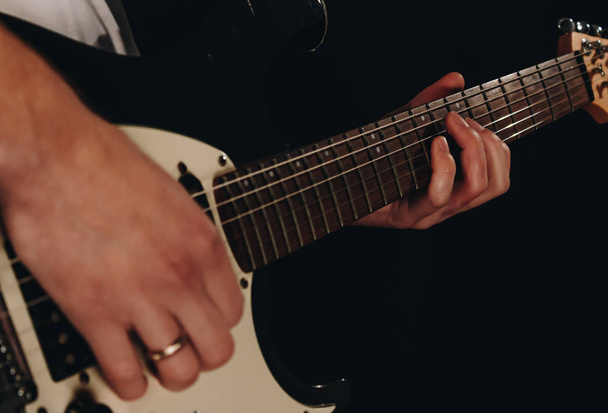 Close up shot of a man with his fingers on the guitar frets - Фото, изображение