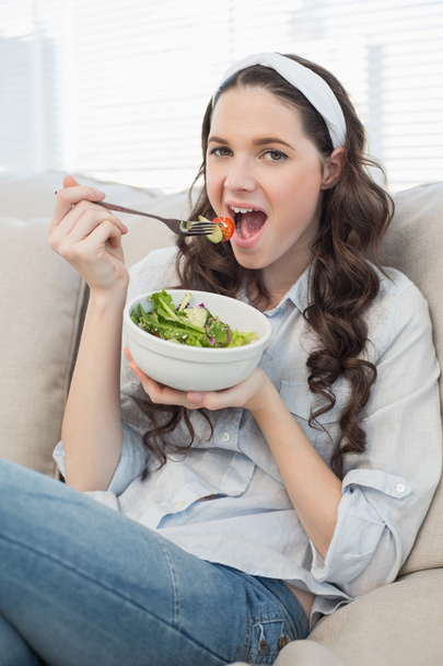 Cute casual woman on cosy couch eating salad - Fotoğraf, Görsel