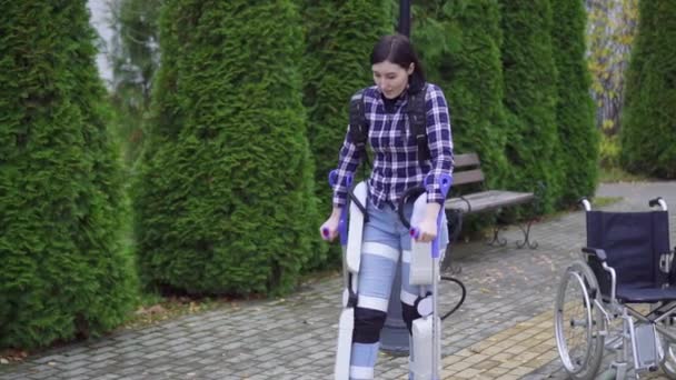 young disabled woman uses exoskeleton to walk in Park - Кадри, відео