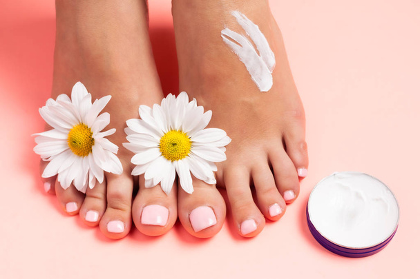 Woman's perfect, groomed feet with of natural herbal cream. Love a feet. Beautiful flowers on pink background. Care about clean, soft and smooth skin on foot. Fresh flowers. - Photo, Image