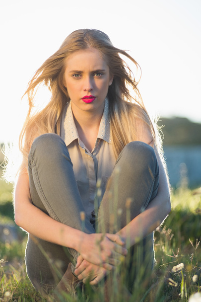 Blonde woman with red lips sitting in grass - Foto, Imagen