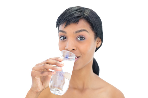 Amused black haired woman drinking a glass of water - Photo, image