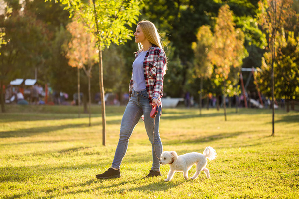 Beautiful woman walking with her Maltese dog in the park. - Fotó, kép