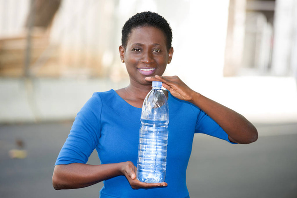 joven feliz mujer sosteniendo una botella de agua mineral en la ciudad
 - Foto, Imagen