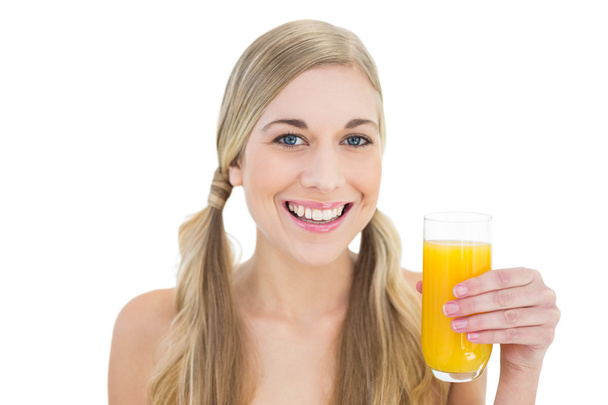 Delighted young blonde woman holding a glass of orange juice - Photo, image