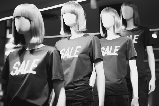 Dámské figuríny v tričkách s nápisem "Prodej" oznamující slevy v nákupním centru. Černobílá fotografie. - Fotografie, Obrázek