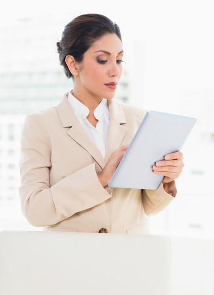 Businesswoman standing behind her chair using digital tablet - Фото, зображення