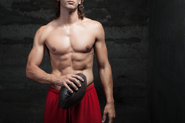 Vista recortada del hombre musculoso desnudo sosteniendo la pelota de fútbol en sus manos
 - Foto, Imagen