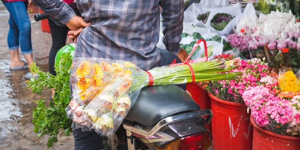 Ho Thi Ky květinový trh v Ho Chi Minh City (Saigon), Vietnam: kytice květin na skútru sedadlo za mužem čeká v blízkosti vědra s květinami. Cestovní atrakce Saigonu, která je mimo-the-beat-path - Fotografie, Obrázek